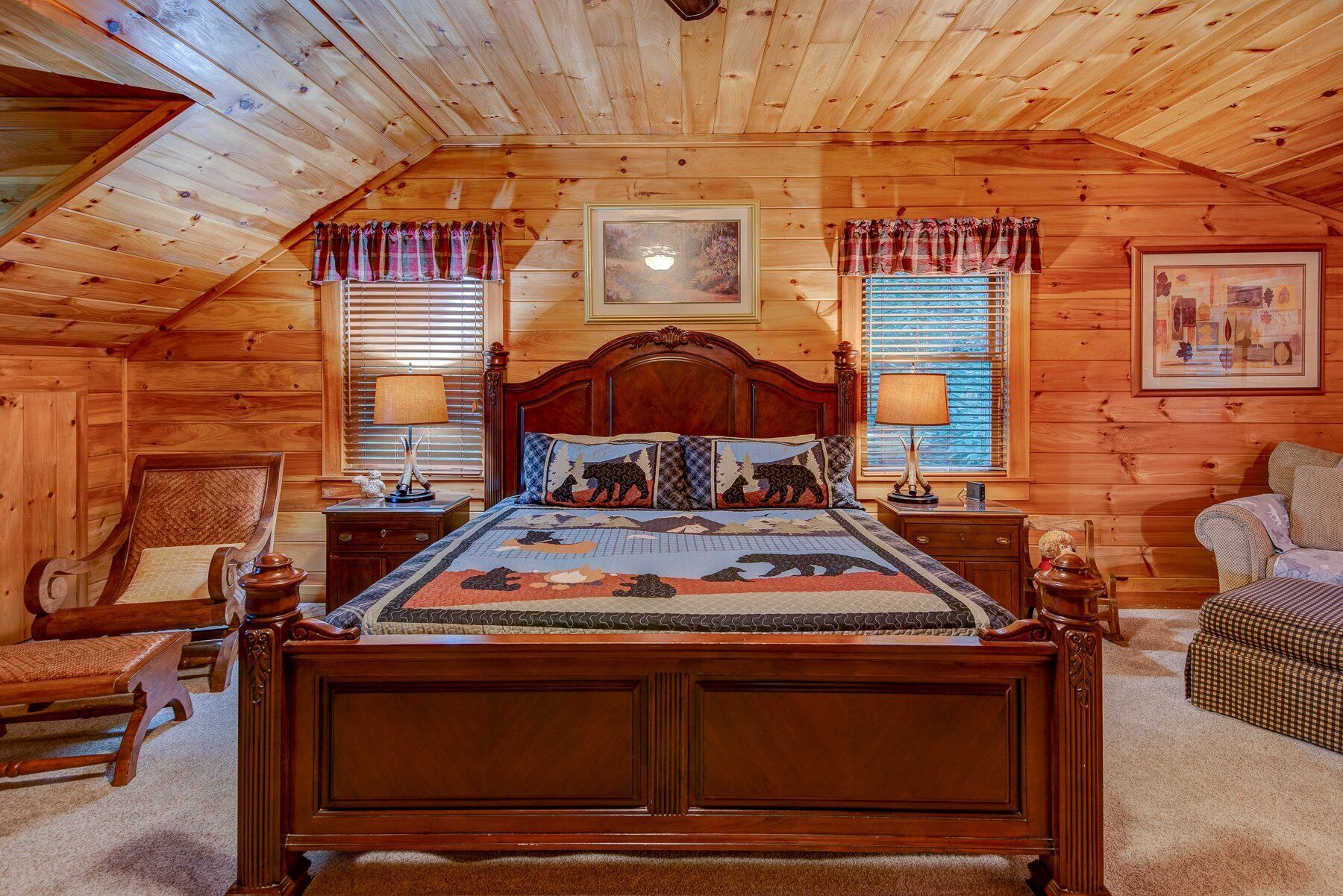 Camera accogliente in legno con un letto di legno, due abat-jour, una sedia e un divano.