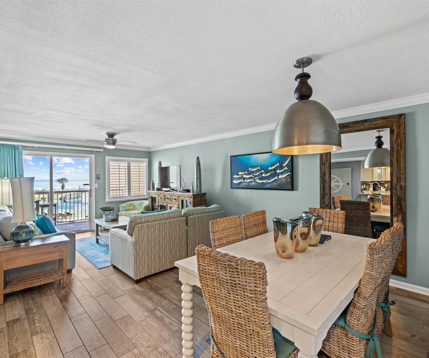 A spacious living area with a dining table, wicker chairs, and a large painting.