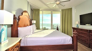Habitación de hotel con una cama grande, ventilador de techo, televisión y vistas al océano.