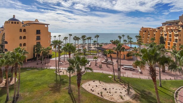 A resort with multiple buildings, palm trees, and a beach view.