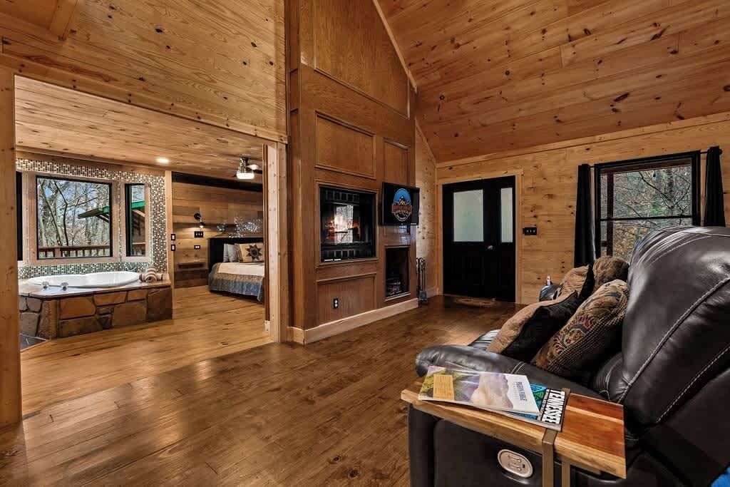 A wooden interior with a living area, a fireplace, and a stone sink.