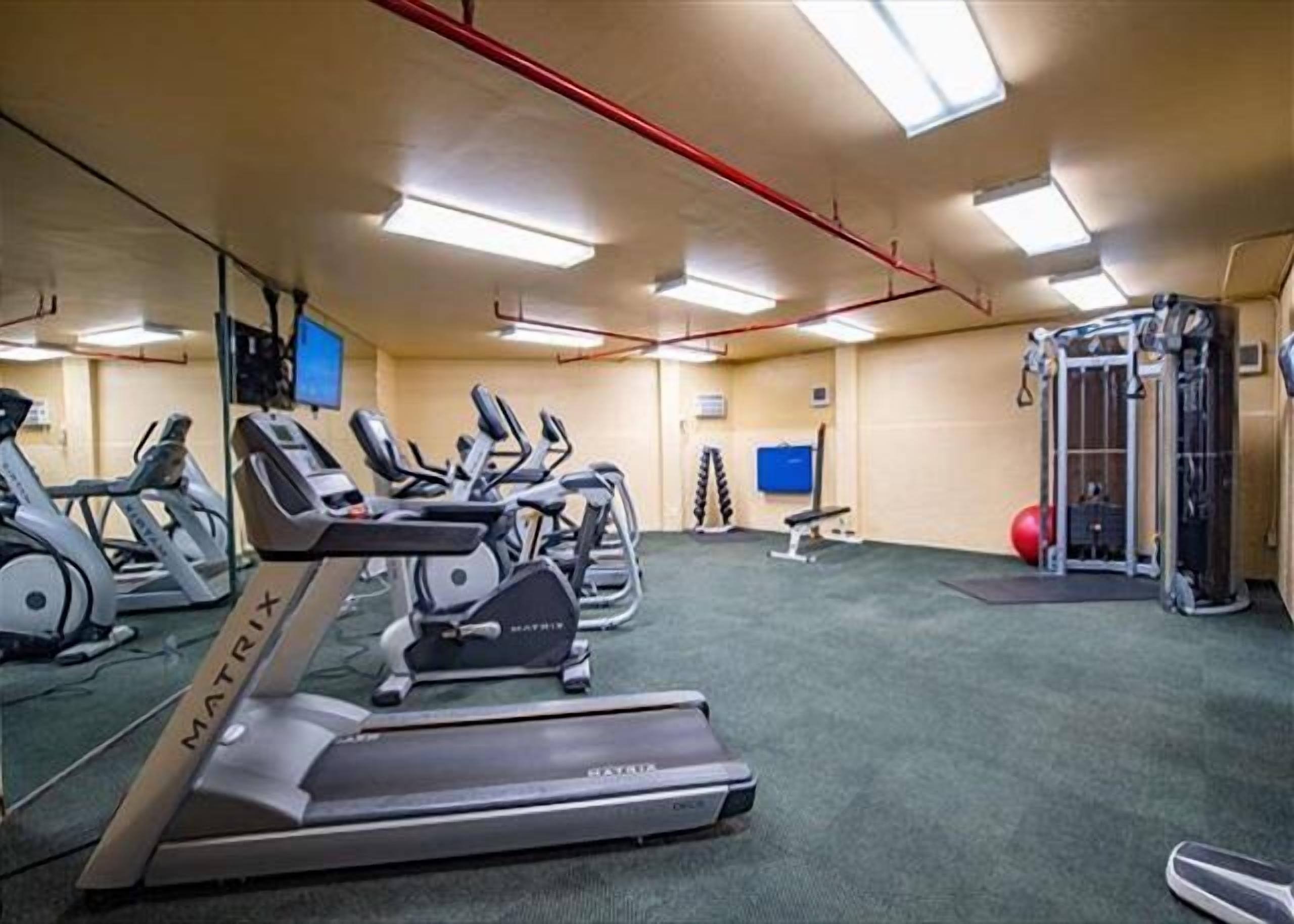 Ett gym med löpband, en bänk och utrustning för styrketräning.