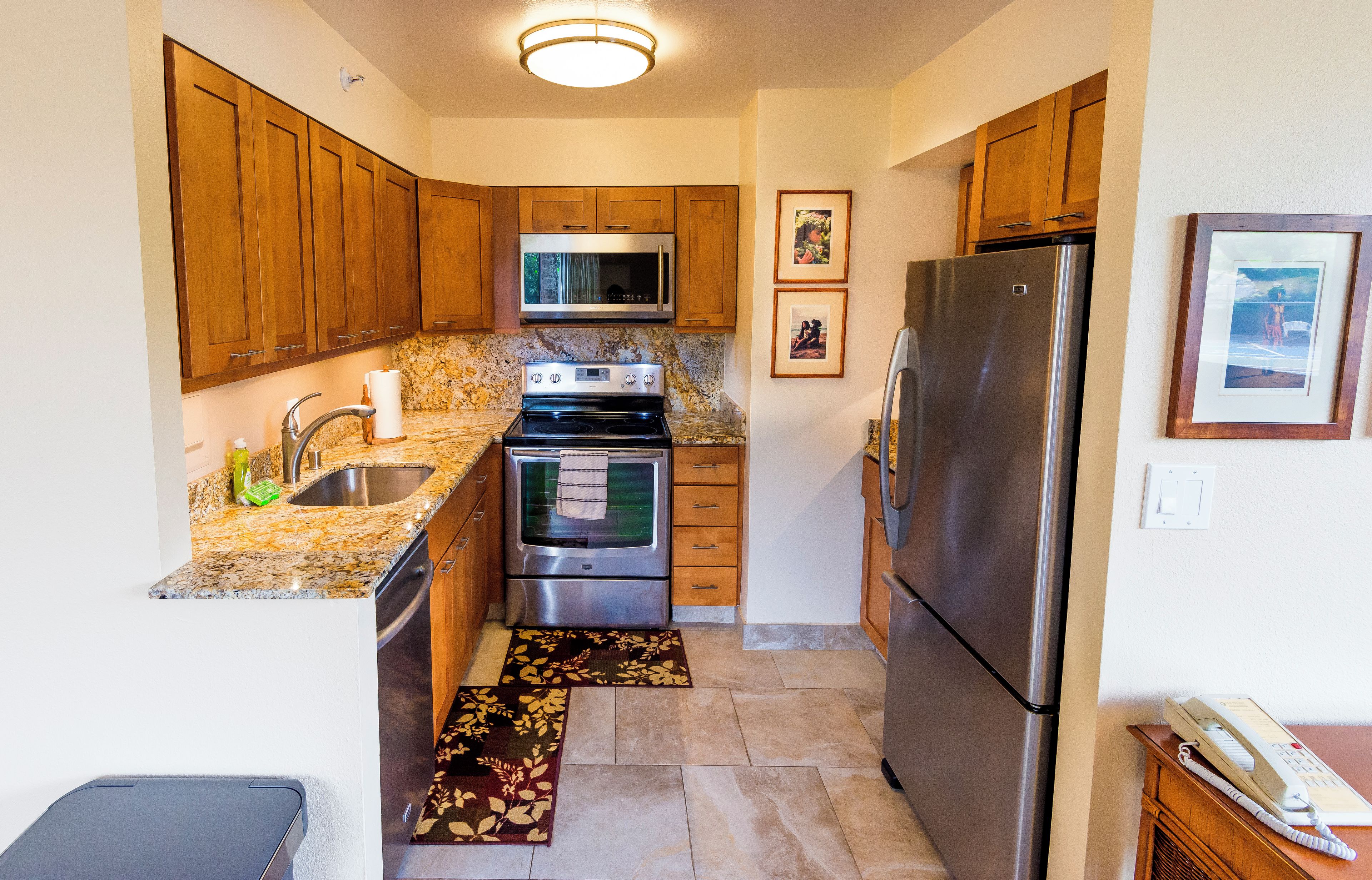 A kitchen with wooden cabinets, stainless steel appliances, granite countertops, and a marble backsplash.
