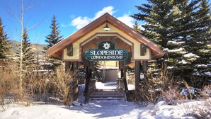 Un edificio de madera con un letrero que dice "SLOPESIDE CONDOMINIUMS" en la entrada.