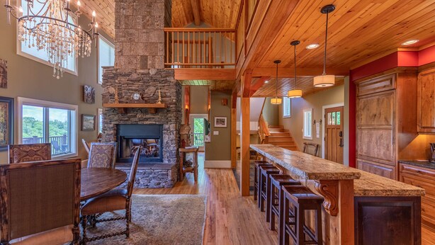 A spacious living area with a stone fireplace, wooden ceiling, and a dining table with chairs. - Stags Leap in Yonahlossee  Pool Table, Indoor Pool, Tennis Courts (Boone)