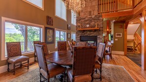 A dining area with a large wooden table, upholstered chairs, and a stone fireplace. - Stags Leap in Yonahlossee  Pool Table, Indoor Pool, Tennis Courts (Boone)