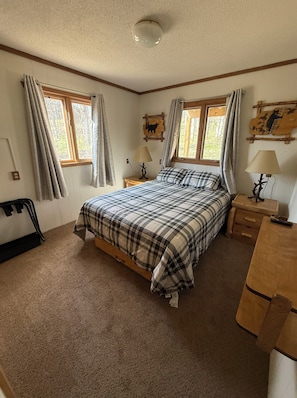 Une chambre à coucher avec un lit, deux tables de chevet, une fenêtre et un luminaire au plafond.