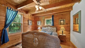 A wooden cabin bedroom with a bed, a ceiling fan, and framed pictures on the walls. - 3 Peaks Lodge - Charming Pet Friendly Cabin with great views, hot tub and pool table! (Vilas)