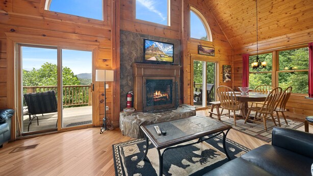 A spacious wooden cabin with a fireplace, a television, and a dining area with chairs and a table. - 3 Peaks Lodge - Charming Pet Friendly Cabin with great views, hot tub and pool table! (Vilas)