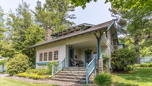 Ein zweistöckiges Haus mit Veranda, Steinstufen und einem kleinen Garten.