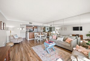 Un salon spacieux avec un canapé gris, une table basse et un coin repas comprenant une table et des chaises blanches.