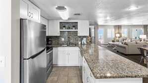 A modern kitchen with white cabinets, granite countertops, and stainless steel appliances.