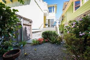 A residential property with a gravel pathway, a wooden fence, and various plants.