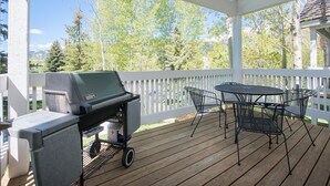 Et overdækket udendørsområde med grill, bord og stole.