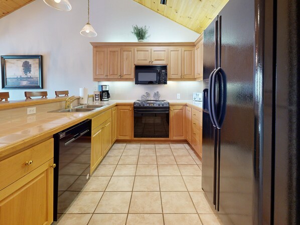 A kitchen with wooden cabinets, a black refrigerator, a microwave, a stove, and a dishwasher.