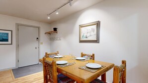 A dining area with a wooden table set for four, surrounded by chairs with patterned cushions.