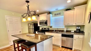 A kitchen with white cabinets, a granite countertop, a stainless steel refrigerator, a microwave, a stove, and a coffee maker. - MI CASA DEL MAR - So close to the beach, perfect house for 4! (Caplen)