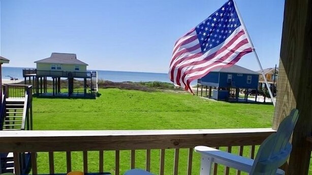 A beach view with an American flag, a wooden deck, and a table with drinks. - MI CASA DEL MAR - So close to the beach, perfect house for 4! (Caplen)