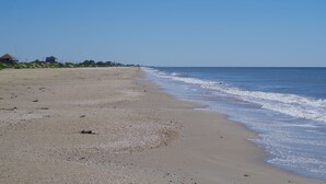 A beach with a clear sky, a sandy shore, and buildings in the background. - MI CASA DEL MAR - So close to the beach, perfect house for 4! (Caplen)