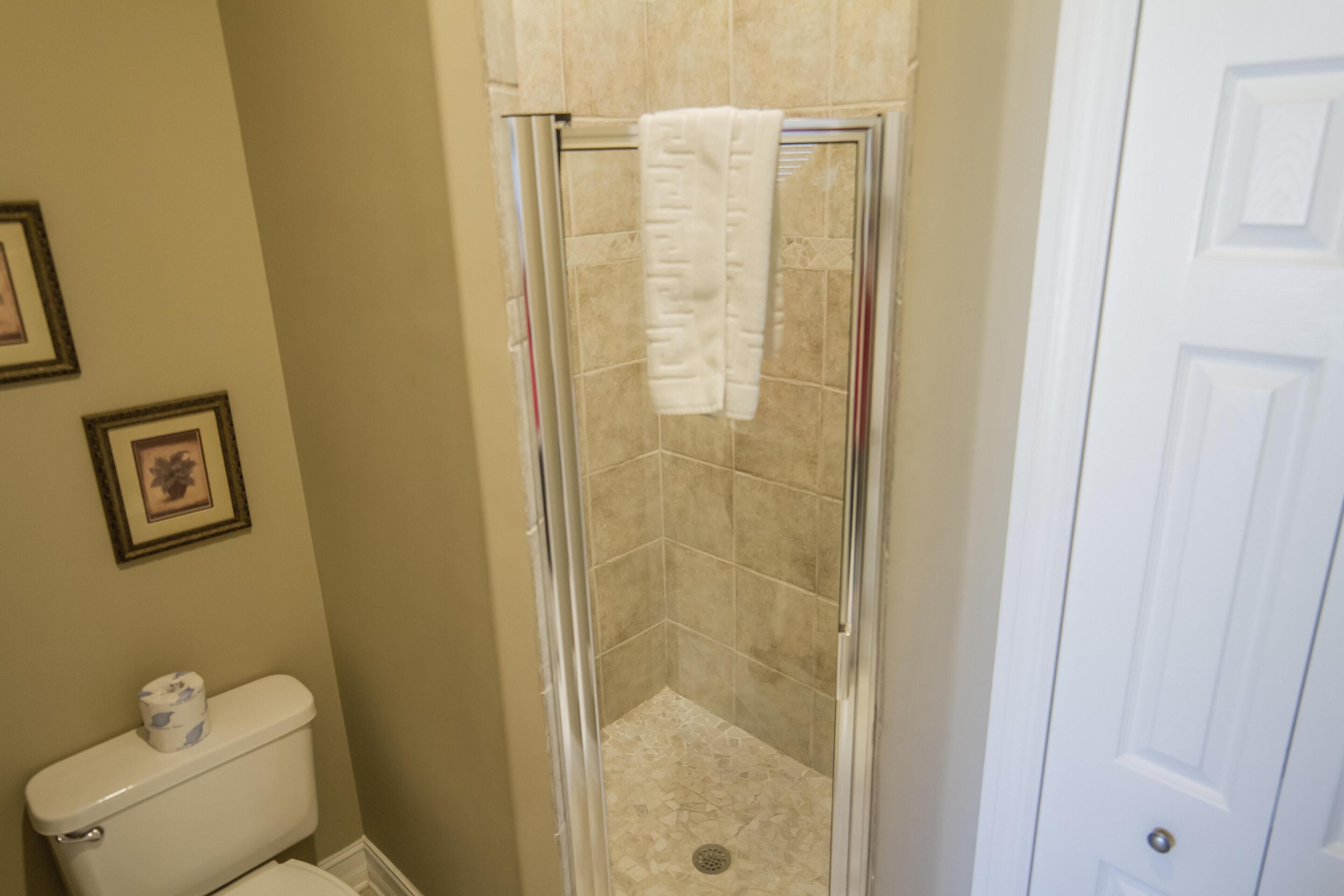 A bathroom with a glass-enclosed shower, a toilet, and a door.