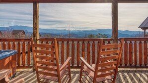 A wooden deck with chairs and a hot tub, overlooking a mountainous landscape. - Priceless View - AWESOME MOUNTAIN VIEWS, $560 FREE tickets each paid day! (Sevierville)