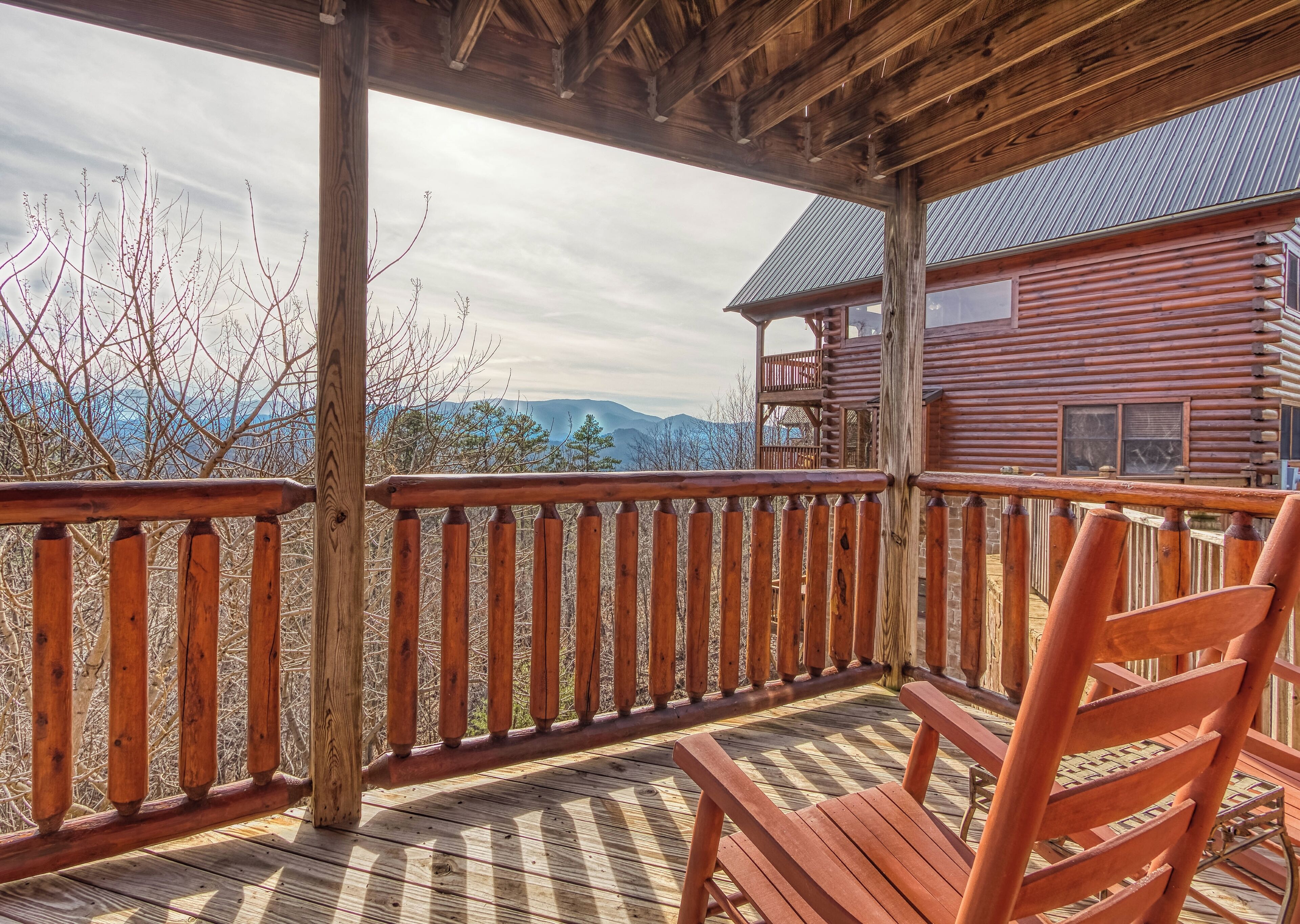 A wooden deck with a wooden chair, overlooking a mountainous landscape.