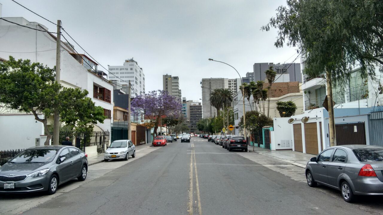 A street lined with parked cars and buildings.