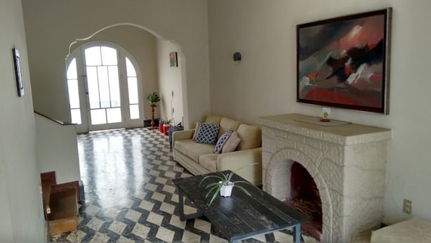 A spacious living room with a fireplace, a checkered floor, a sofa with cushions, and a painting on the wall. - Guest House Miraflores (Lima)