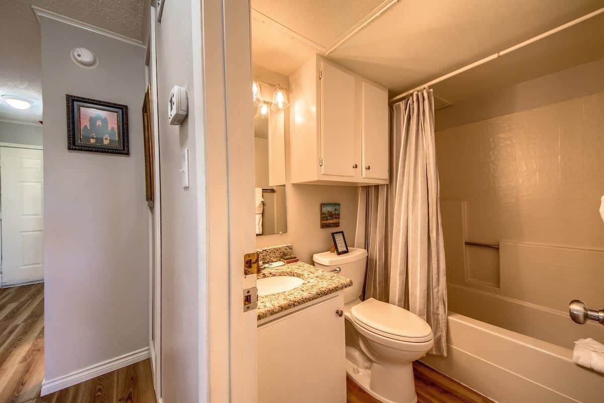 A bathroom with a toilet, sink, vanity, and shower curtain.