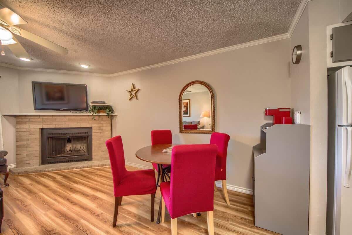 A dining area with a fireplace, a television above it, and a red dining set.