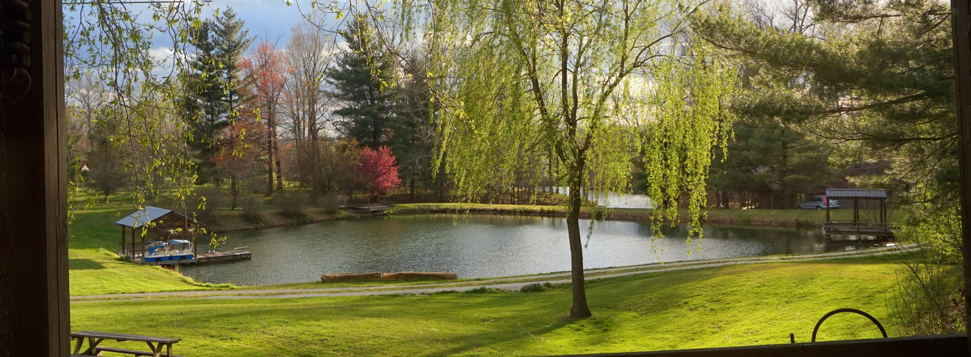 A serene lakeside view with a dock, picnic table, and a small boat.