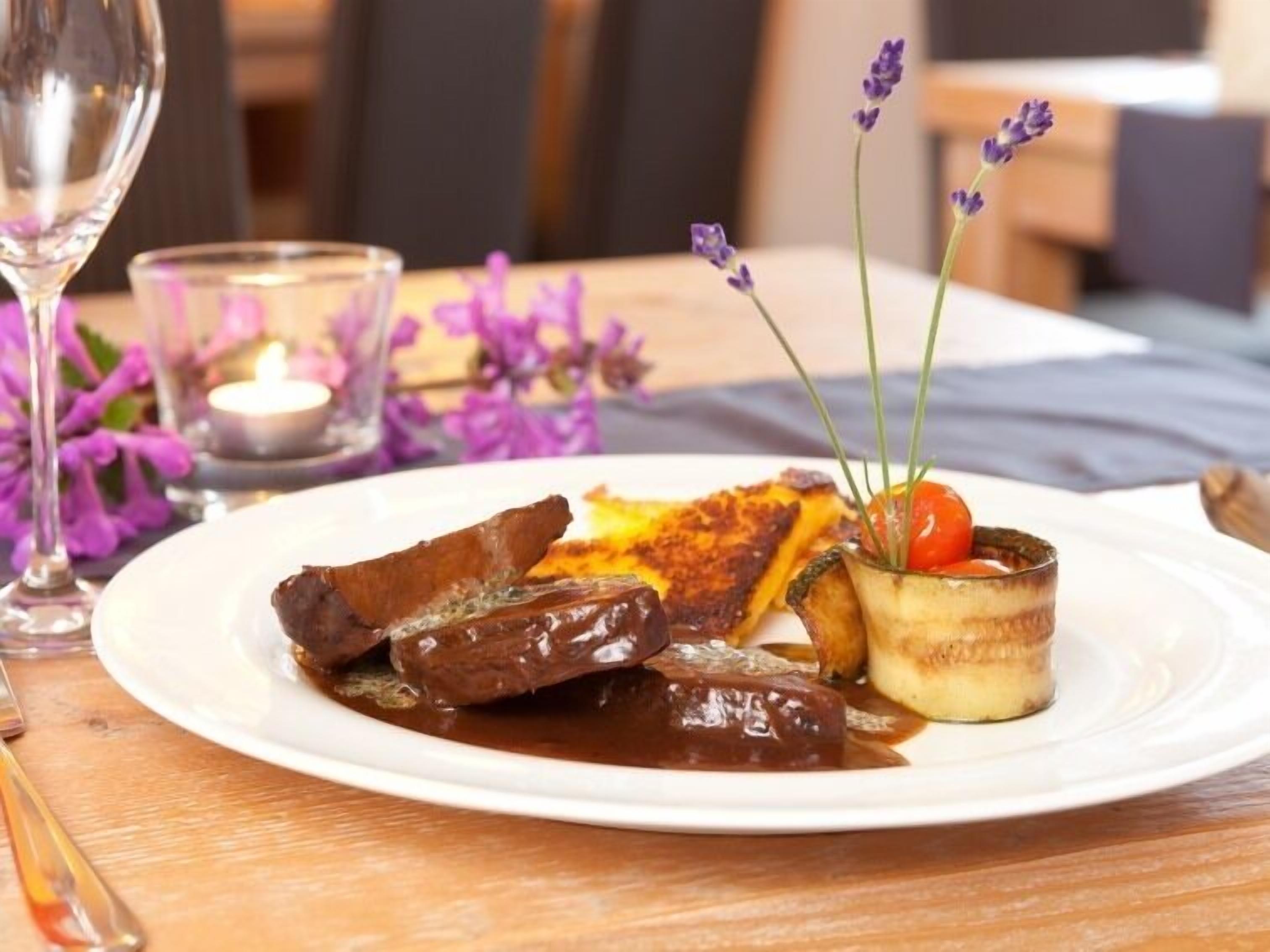 A plate of food with steak, fries, and a small dish with a cherry and herbs.