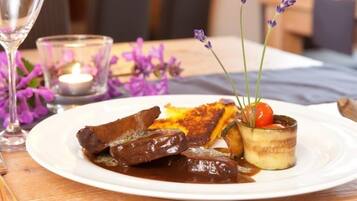 A plate of food with steak, fries, and a small dish with a cherry and herbs.