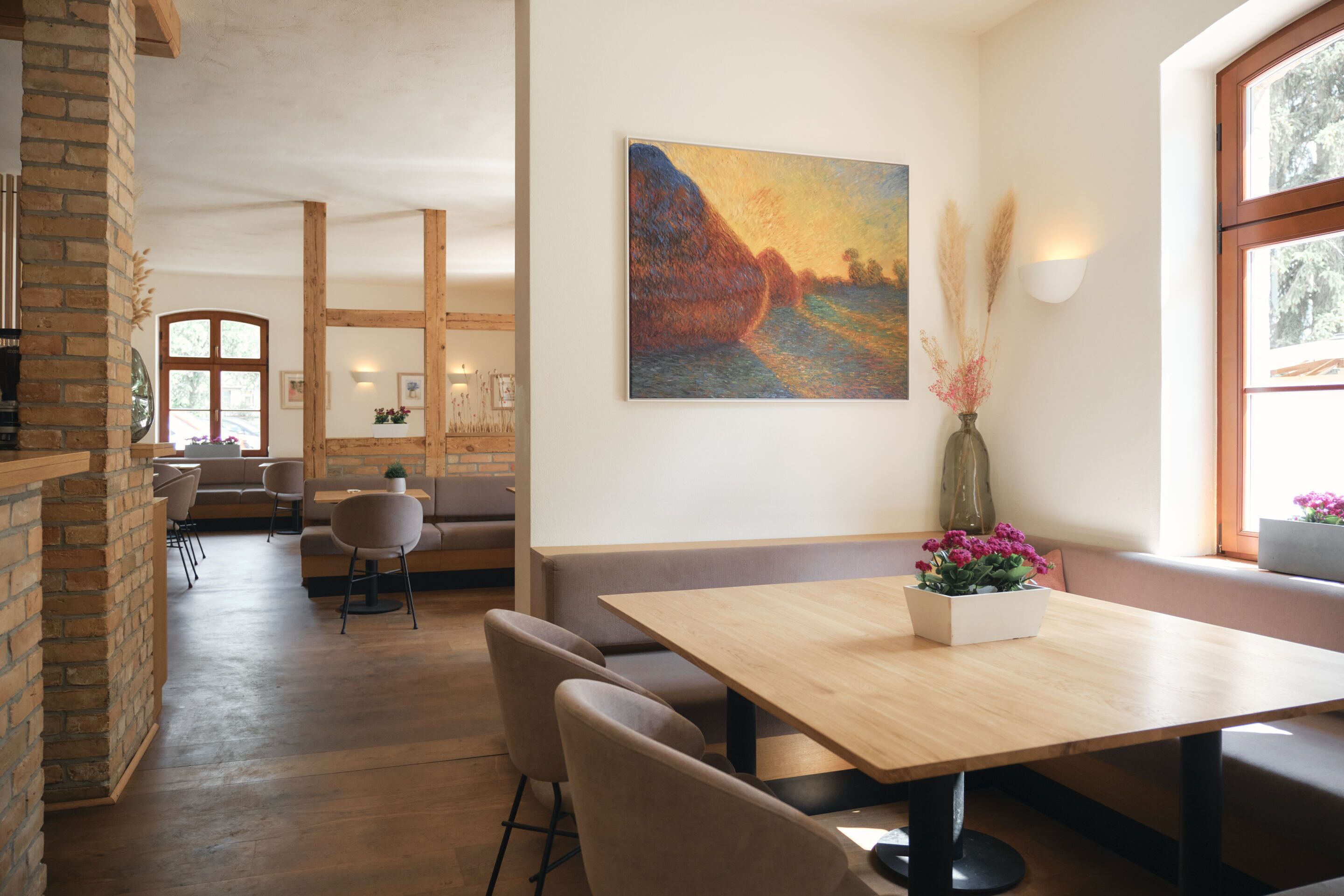Un comedor con una mesa y sillas de madera, un cuadro en la pared y un jarrón con flores.