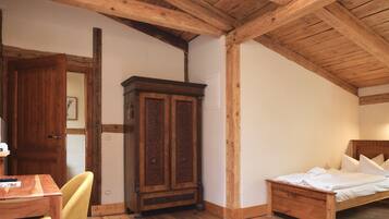 Un dormitorio con techo, cama, armario y escritorio de madera, y una silla.