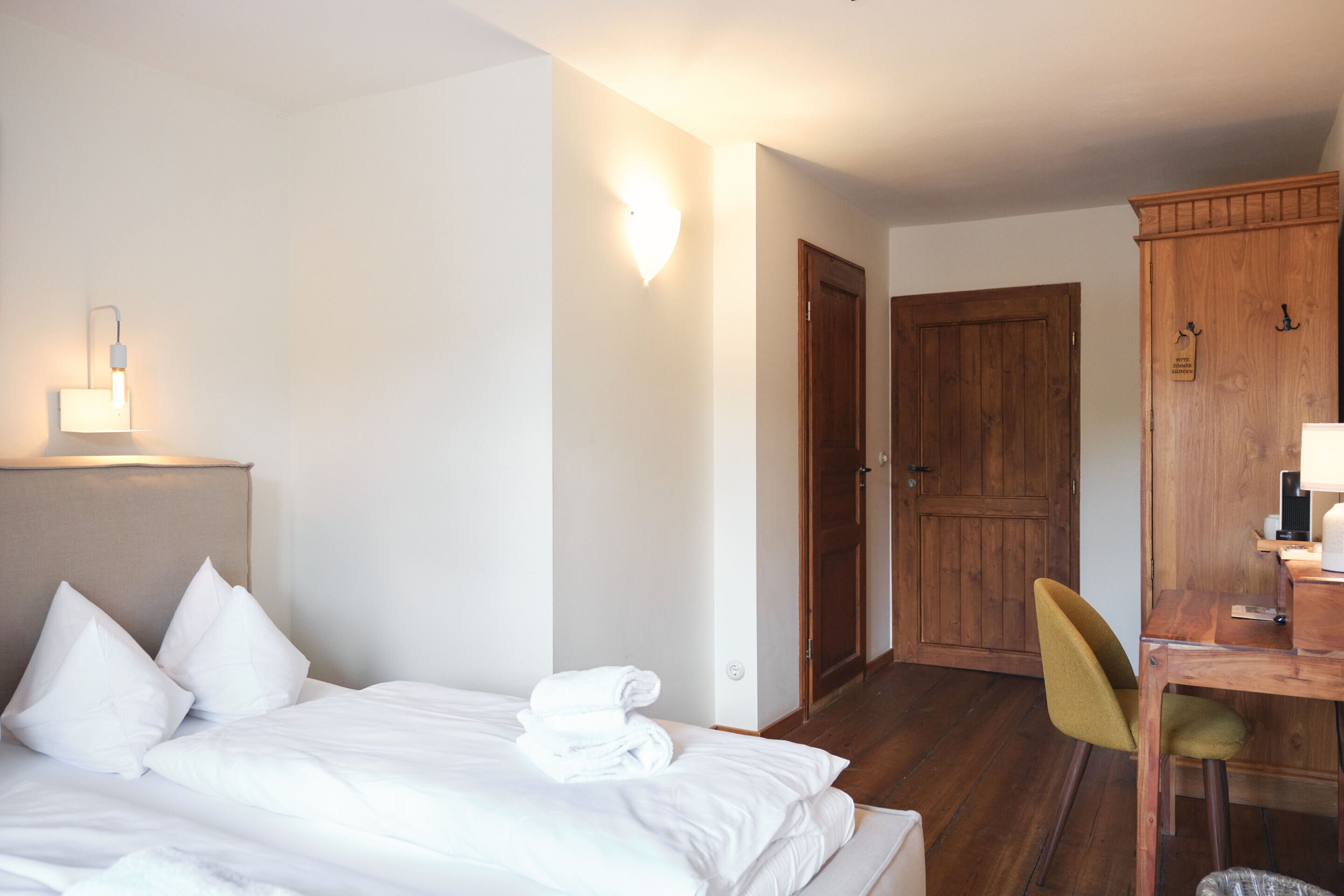 Una habitación de hotel con cama, escritorio, silla y armario.