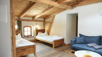 Una habitación con vigas de madera, una cama, un sofá y una pequeña mesa.