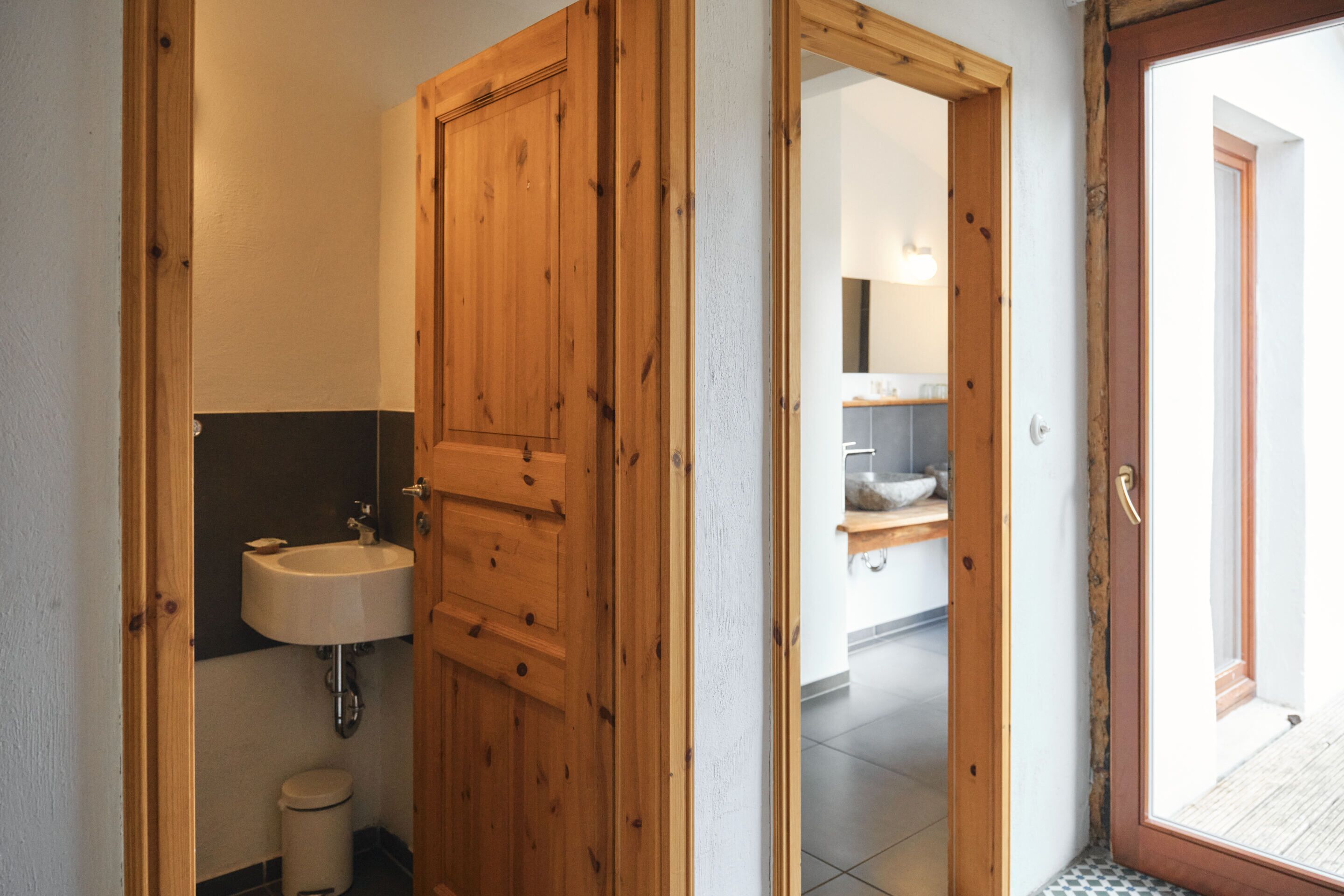 Eine Holztür zu einem Badezimmer mit Waschbecken und Toilette.