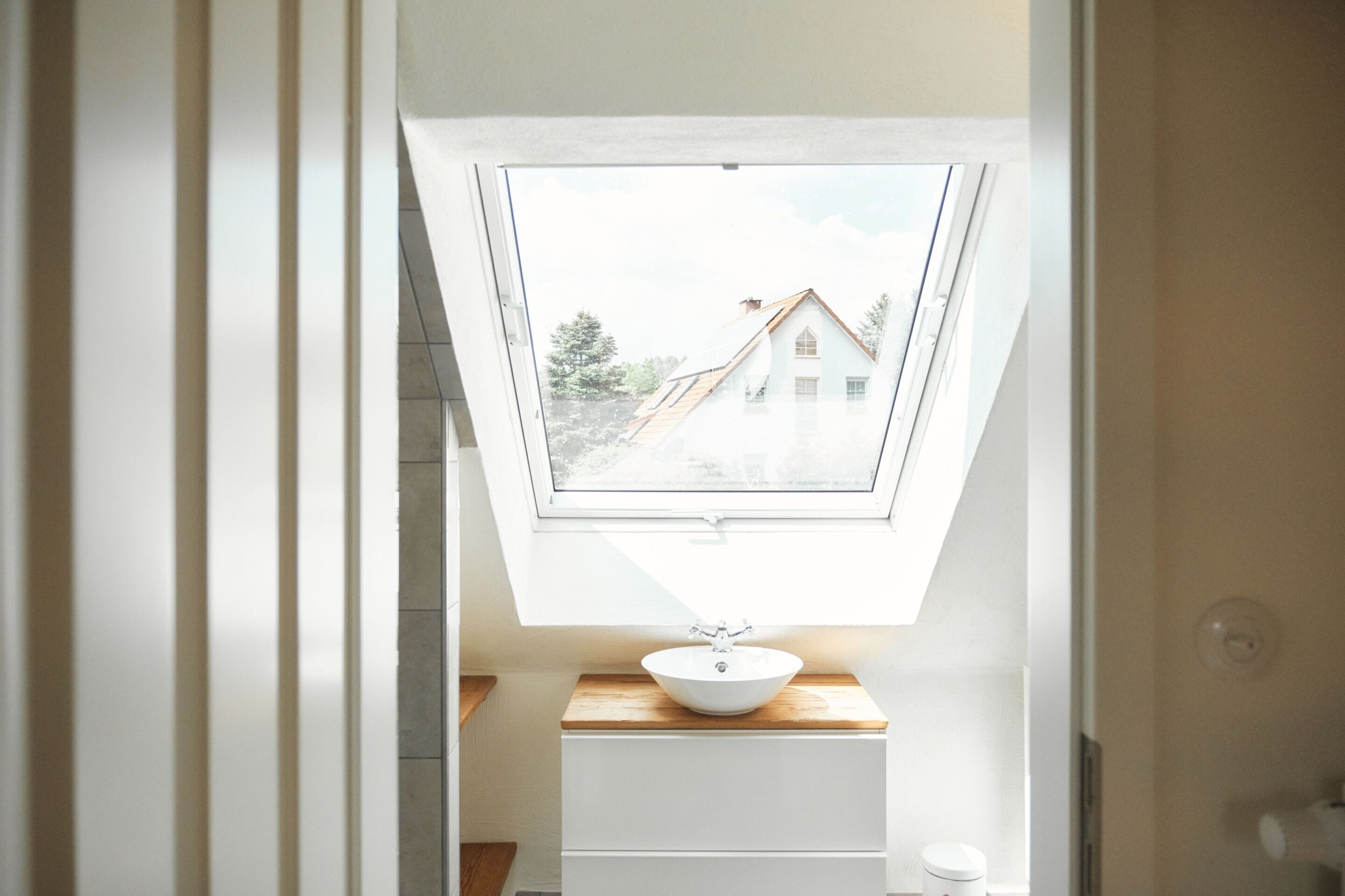 Ein Oberlicht über einem Waschbecken mit Blick auf ein Haus durch das Fenster.