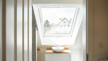 Ein Oberlicht über einem Waschbecken mit Blick auf ein Haus durch das Fenster.