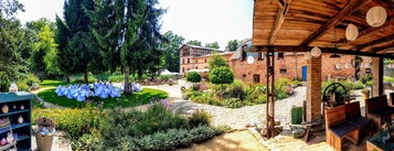 Un patio con zona de estar, un edificio de ladrillo y una pérgola de madera.