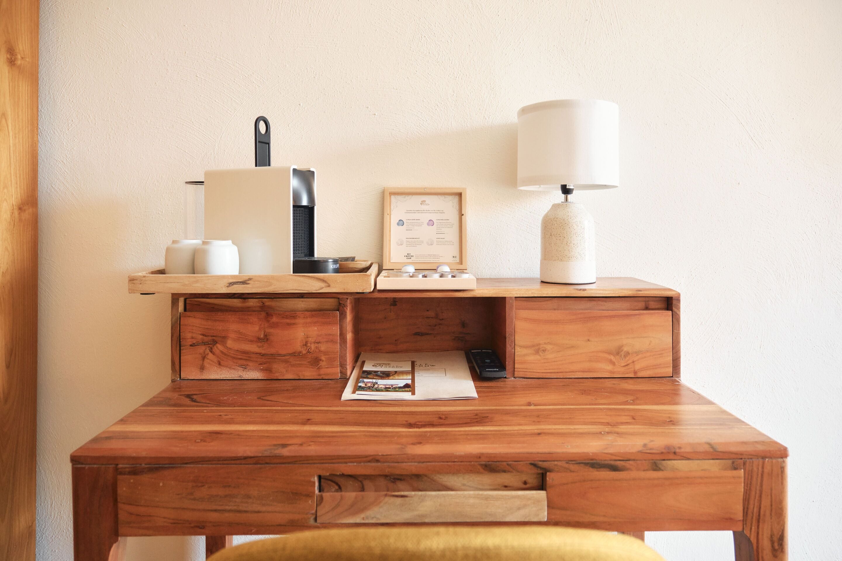 Ein Holztisch mit Lampe, einem gerahmten Zertifikat und einer Kaffeemaschine.