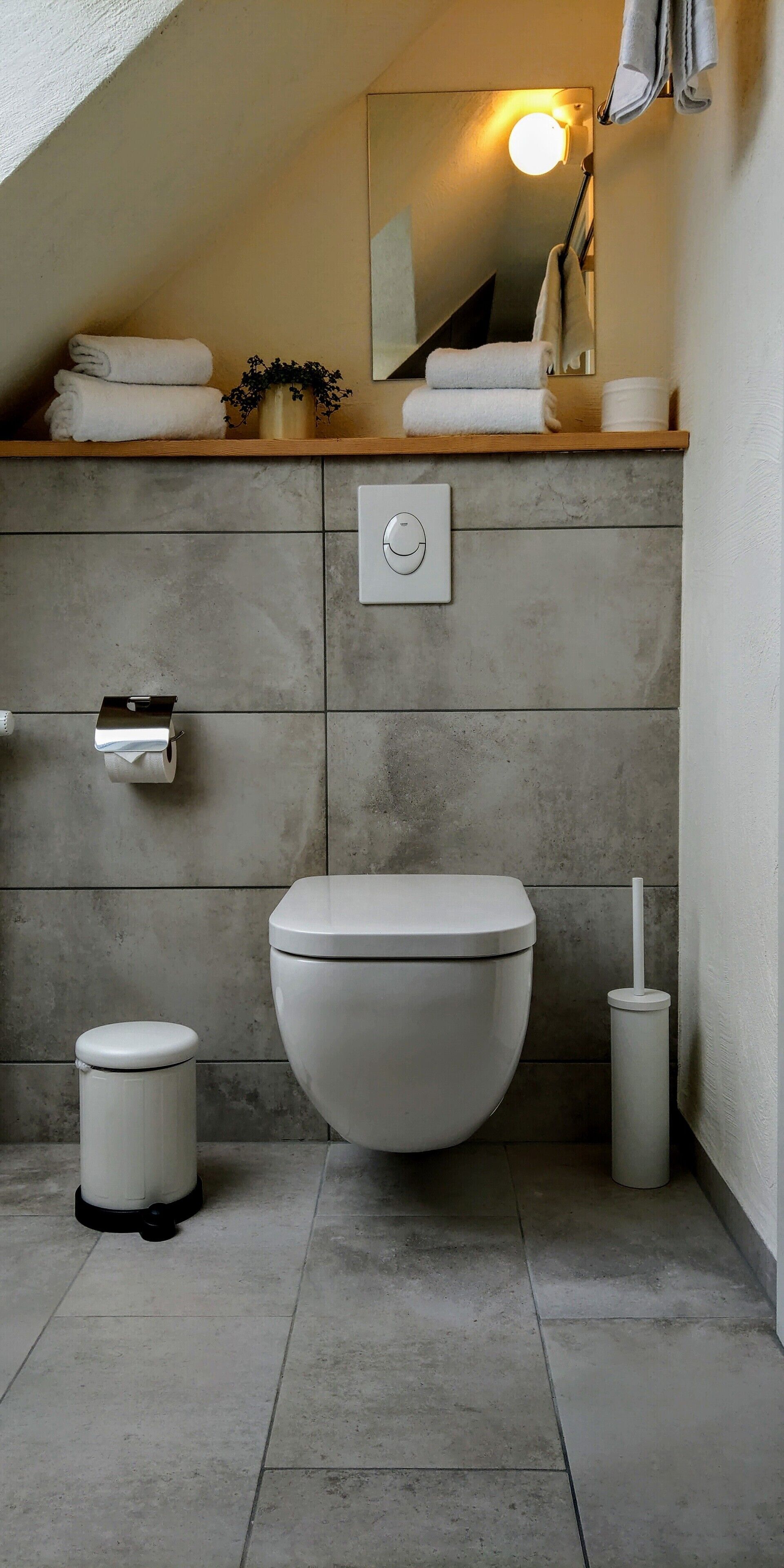 A modern bathroom with a toilet, bidet, and waste bin.