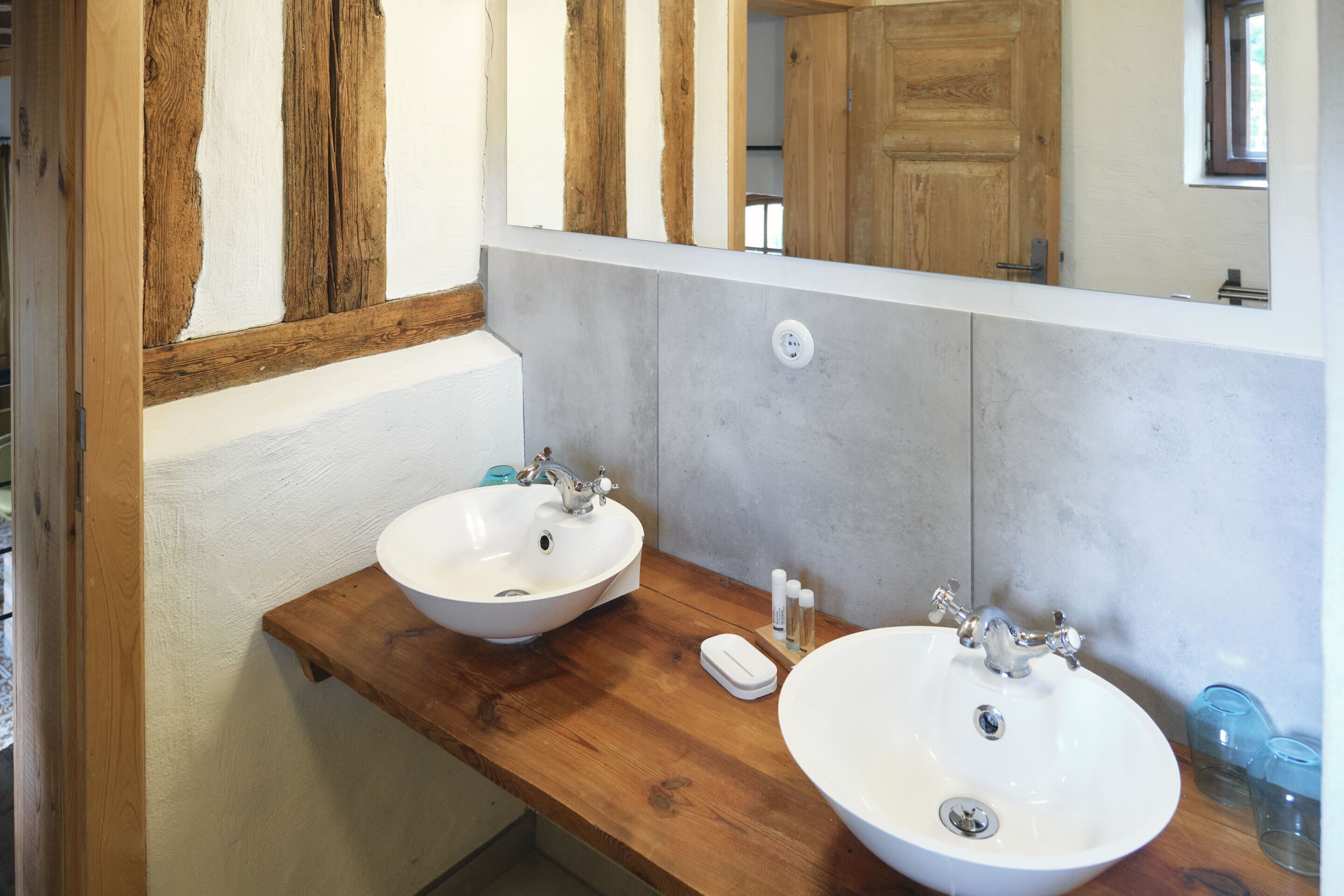 Une salle de bain avec deux lavabos, un plan de toilette en bois et un grand miroir.