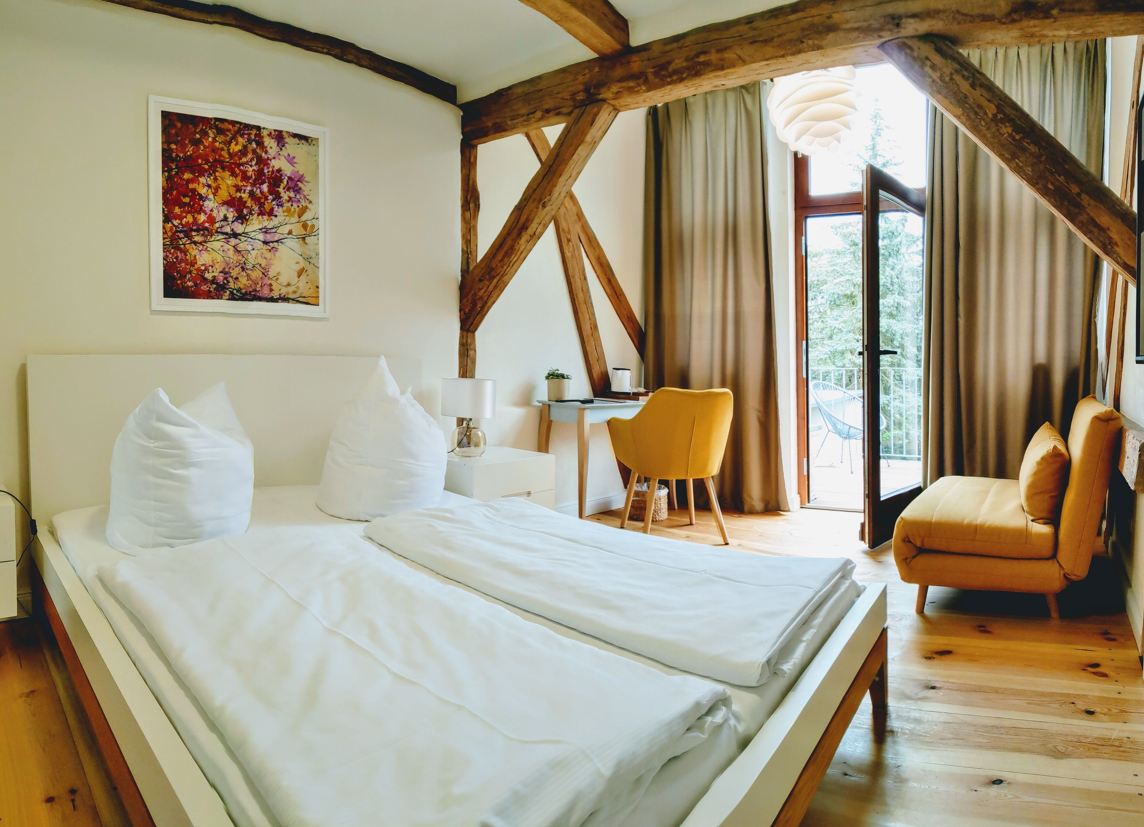 A room with a bed, a desk, a chair, and a large window.