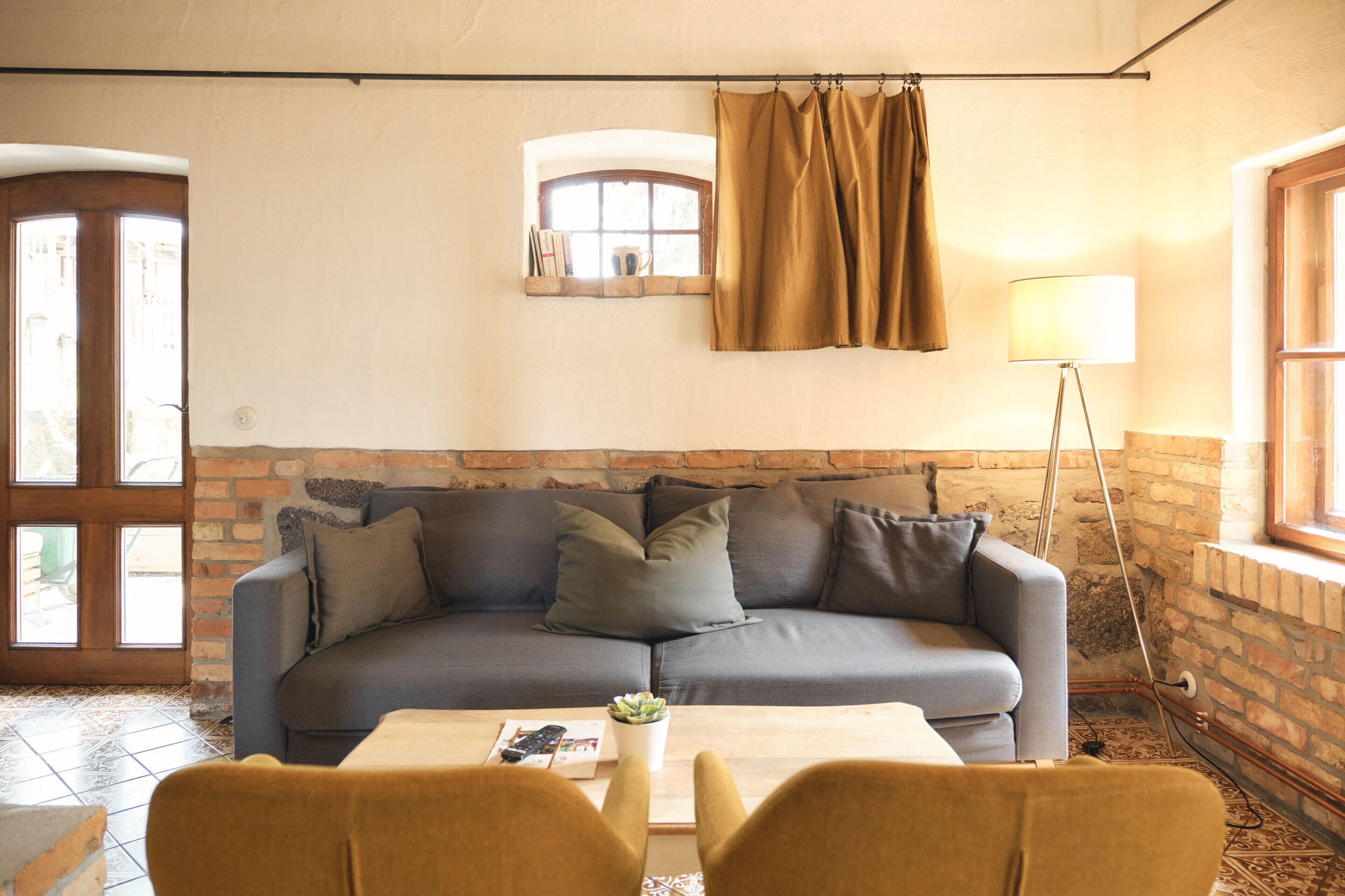 Un salon chaleureux avec un canapé gris, une petite table sur laquelle est posée une plante et une lampe.