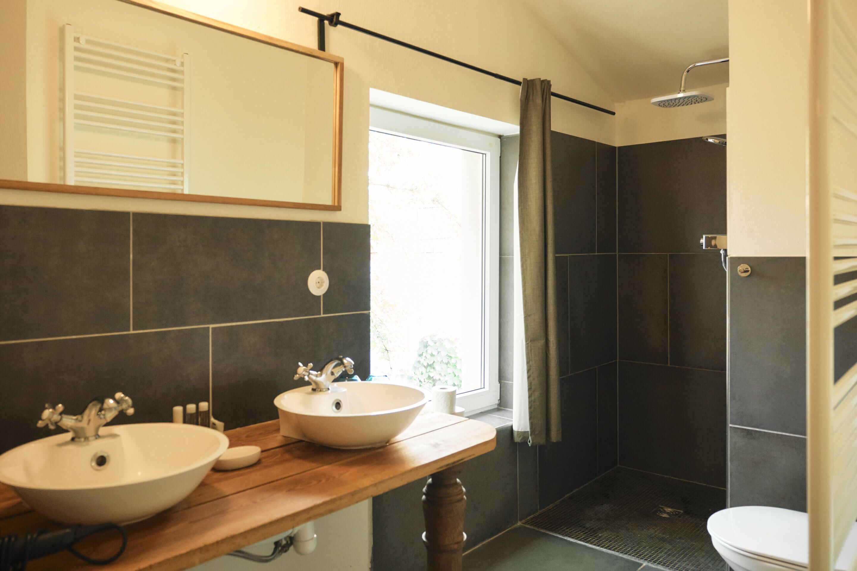 Une salle de bain avec deux lavabos, un miroir, une douche et des toilettes.