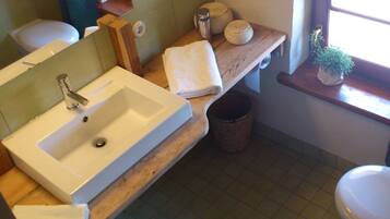 A bathroom with a white sink, wooden countertop, and a window with a plant.