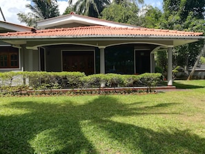 A house with a tiled roof, a covered porch, and a well-maintained lawn.