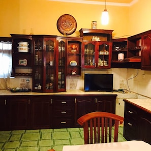 A kitchen with wooden cabinets, a television, and a green checkered tablecloth.